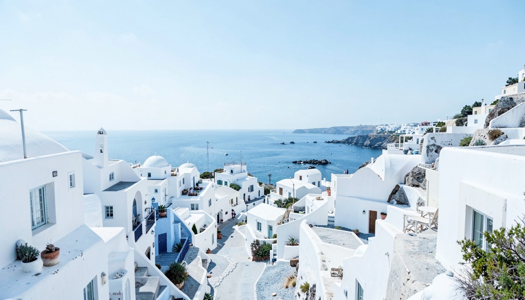 Wide banner of a sunlit whitewashed coastal village scene in soft blue and white tones, calm and inviting mood